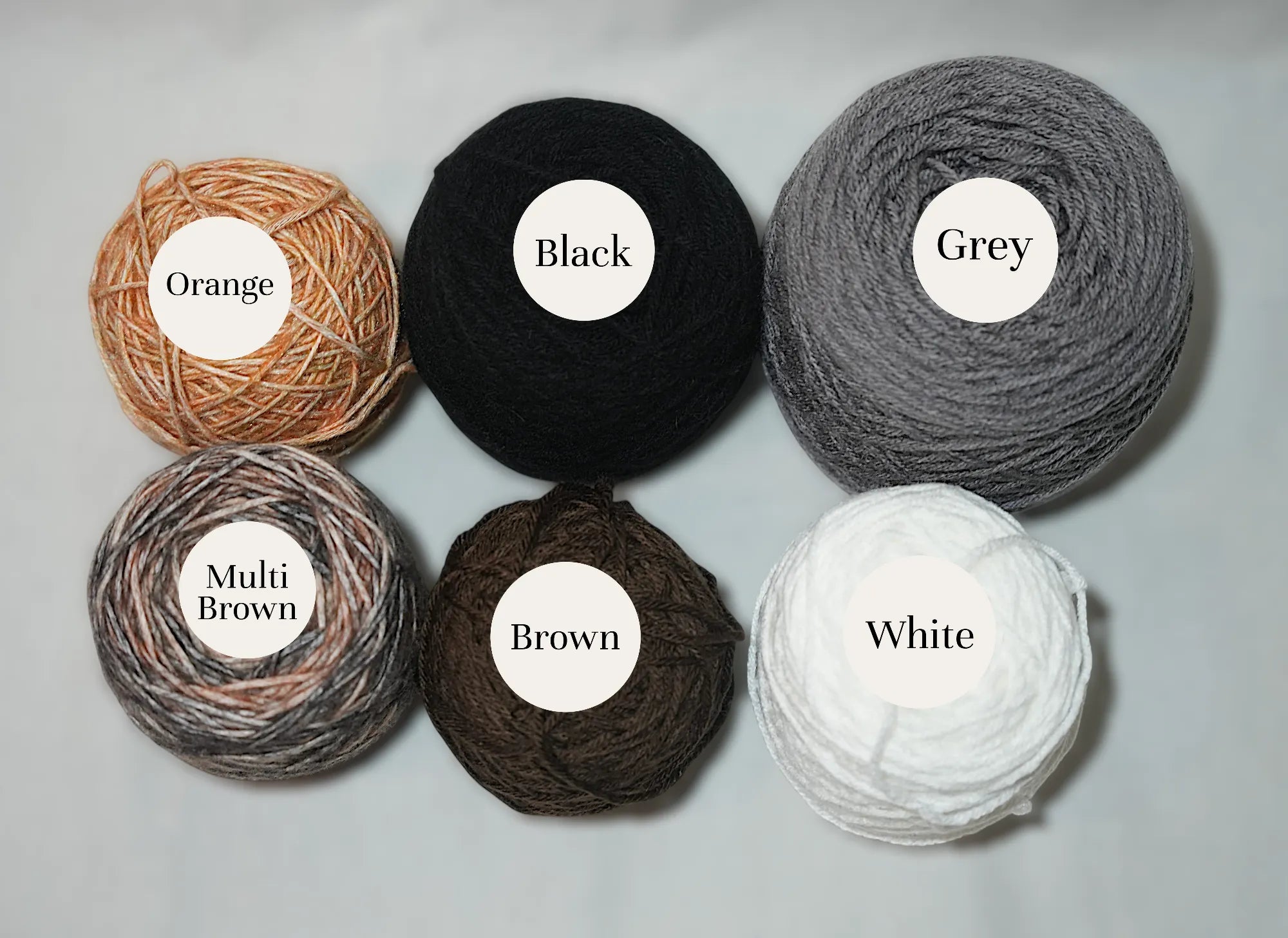 Various colored balls of yarn, including orange, black, grey, multi brown, brown, and white.