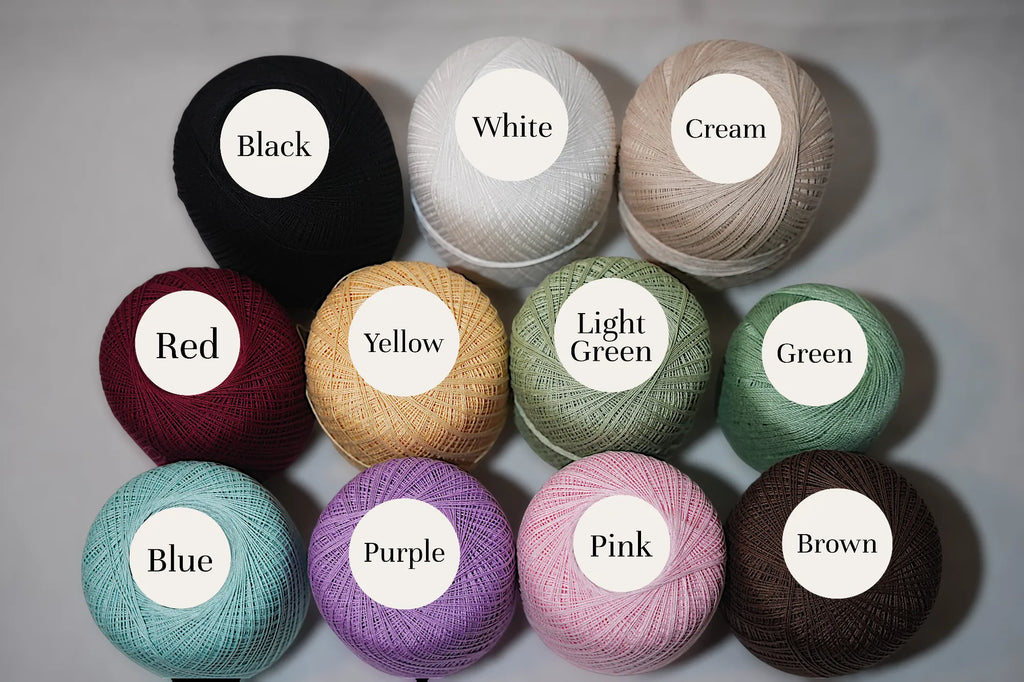 A collection of eleven colorful yarn spools labeled with colors: black, white, cream, red, yellow, light green, green, blue, purple, pink, and brown.